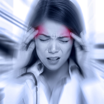 Young woman with a pounding headache or migraine standing clutching her temples with an expression of pain