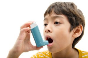 Little boy using Asthma inhaler for breathing on white background