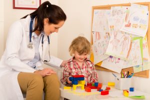 Female pediatrician playing with little girl at medical office