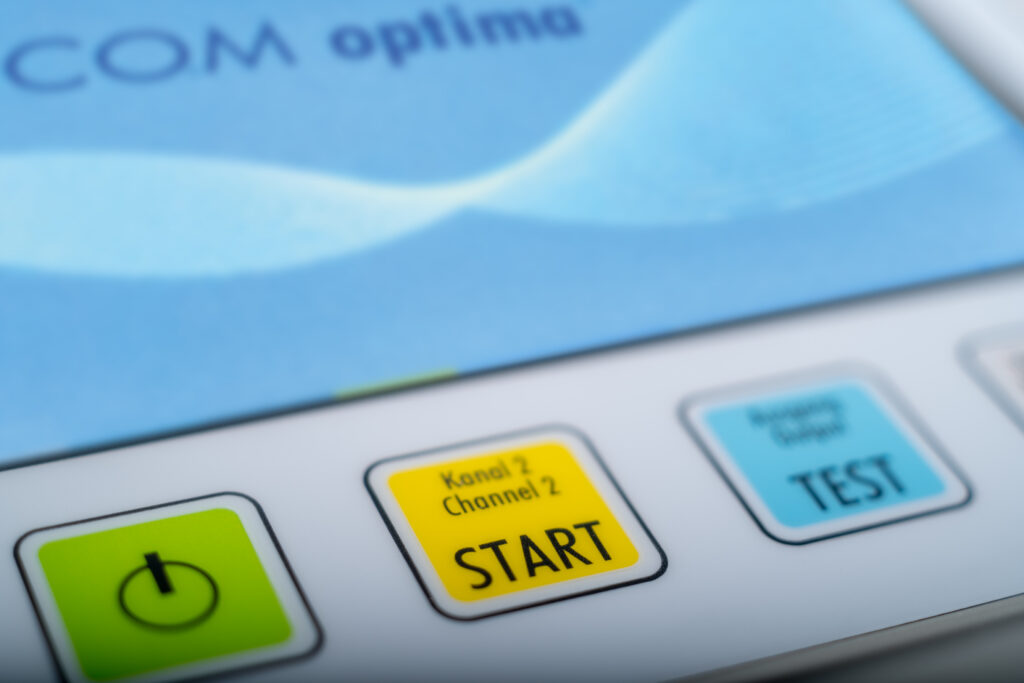 Close view of the BICOM optima panel buttons: power, channel two start, output test